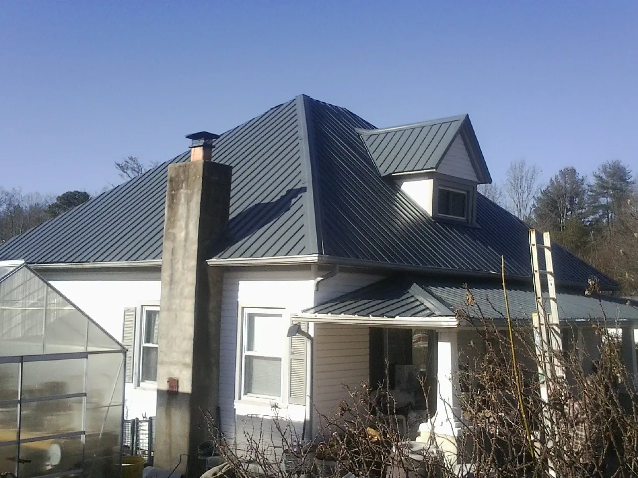 Dark blue standing seam metal roof on a white farmhouse with dormer — Slate & Tile Roof Repair by Roofing Brothers in Blue Island