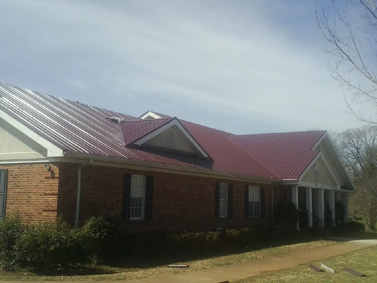 Red metal roof with gabled entries on a long brick building in Blue Island