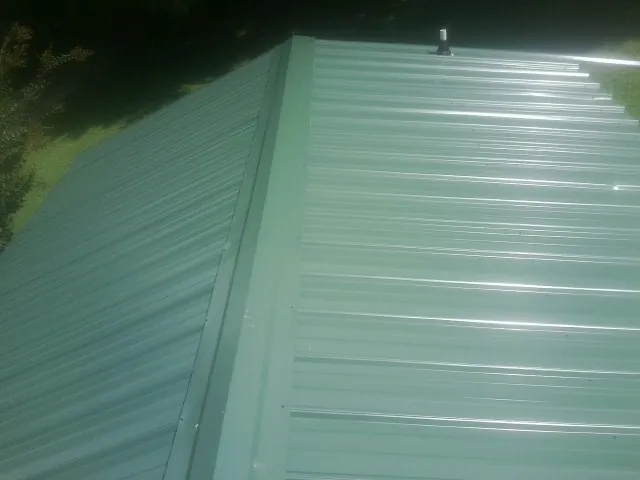 New green metal panels meeting at the ridge of a roof — Flat Roof Repair work by our crew in Blue Island