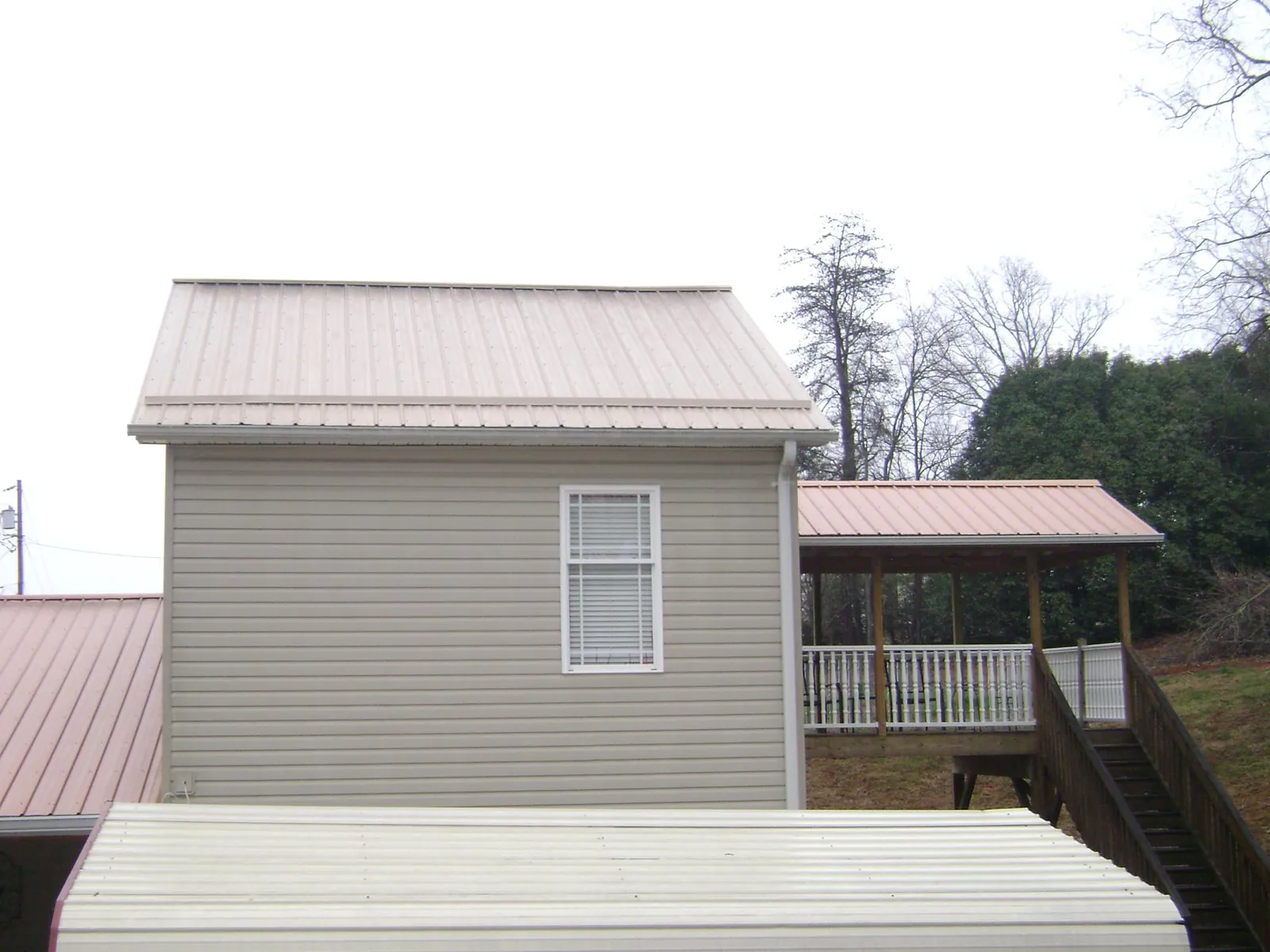 Tan metal roofs on a two story addition and attached porch, from a Roof Replacement job in Blue Island