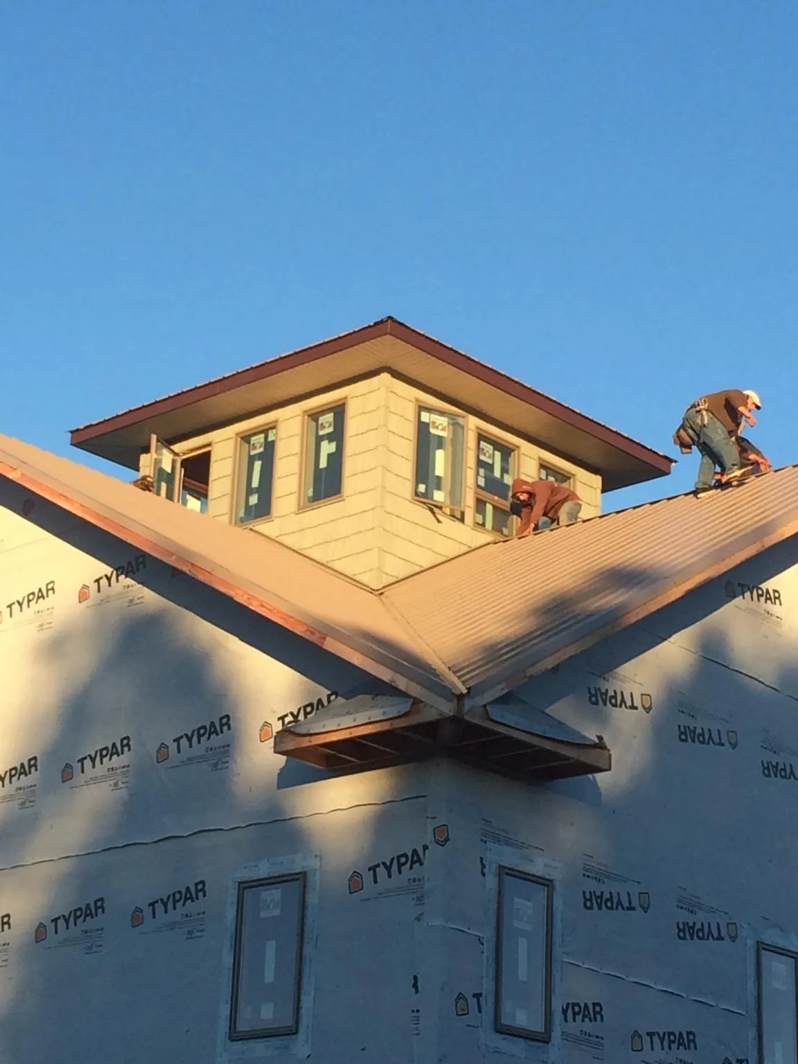 Roofers working around a rooftop cupola on a new metal roof at sunset — Roof Waterproofing in Blue Island by Roofing Brothers